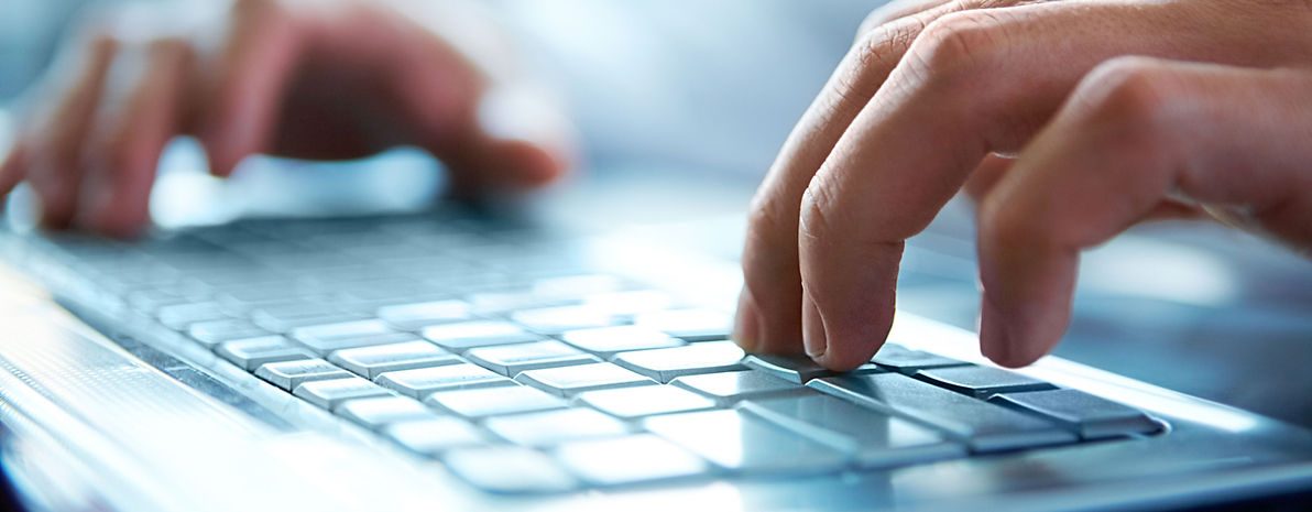 Hands typing on a laptop keyboard